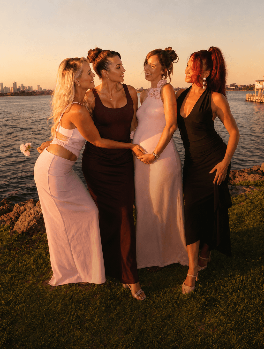 Four friends in hired and borrowed dresses on the Perth foreshore at golden hour